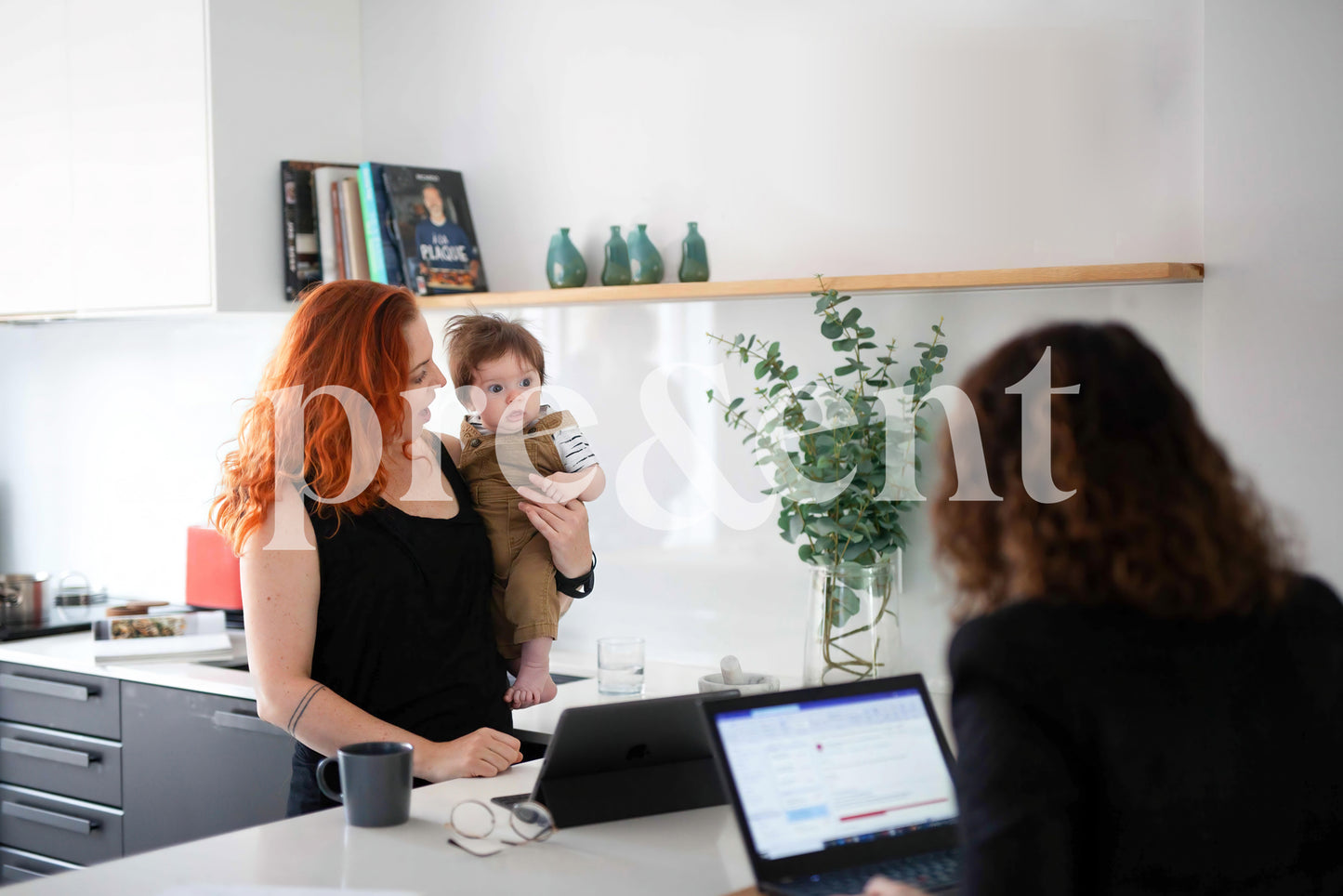 Person holding a newborn while multitasking