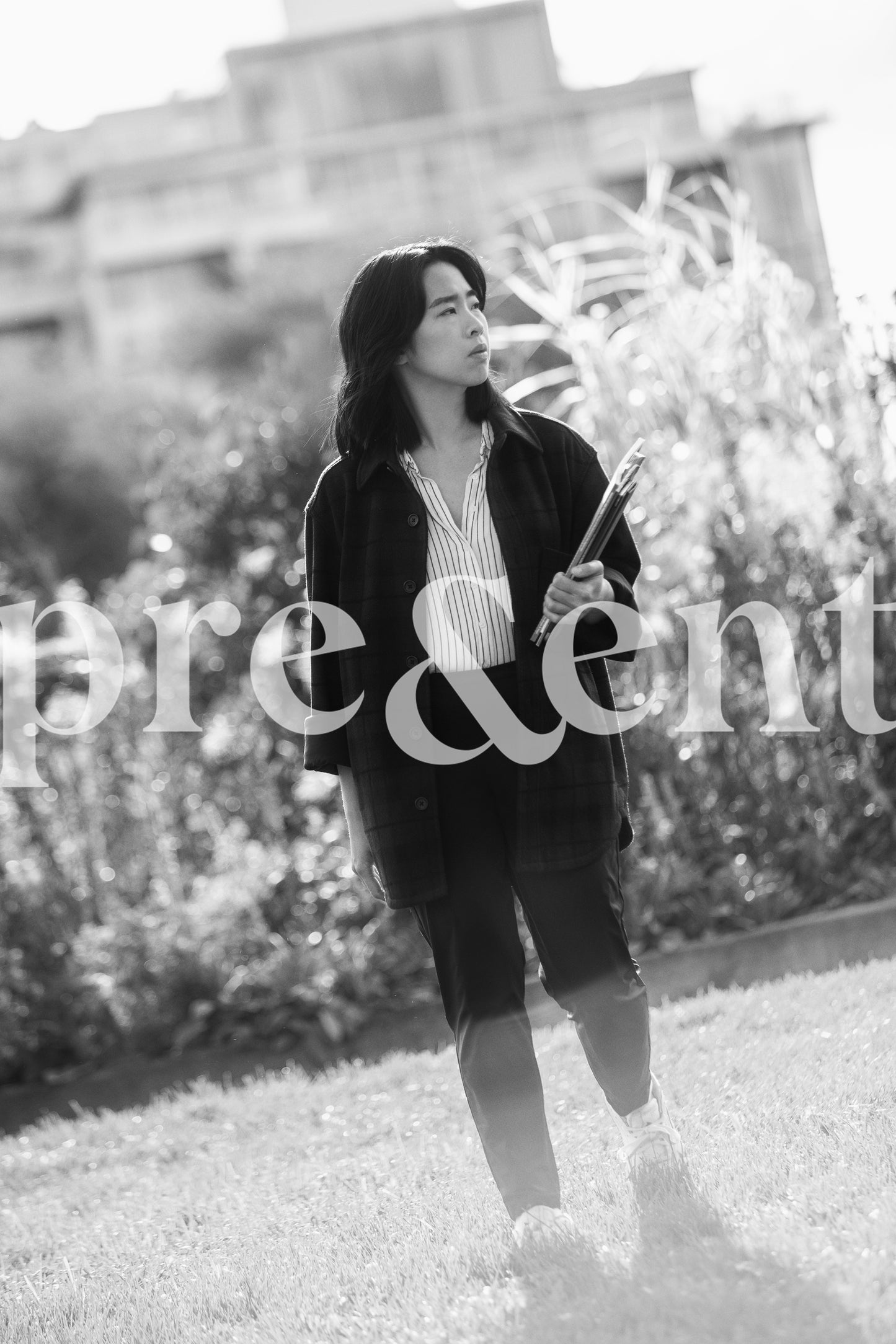 Someone walking in grass while holding notebooks