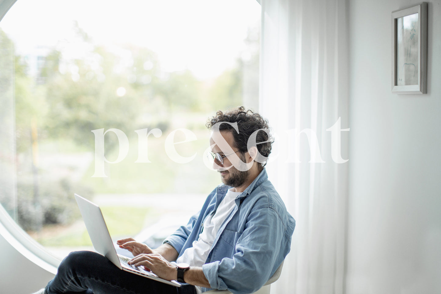 Typing on a laptop by a window