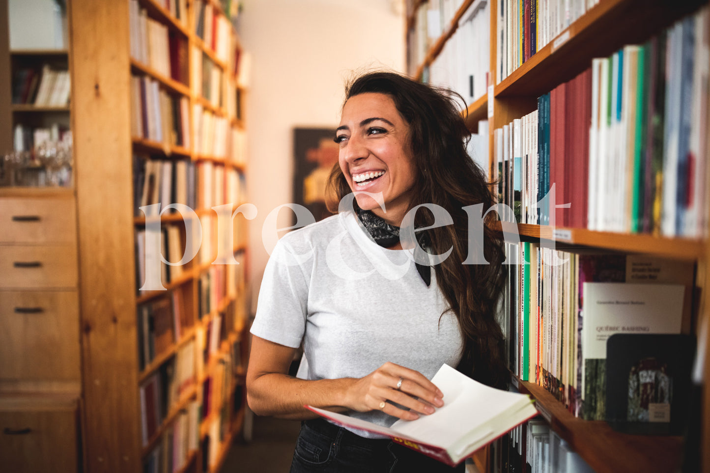 Smiling person in a library, holding a book