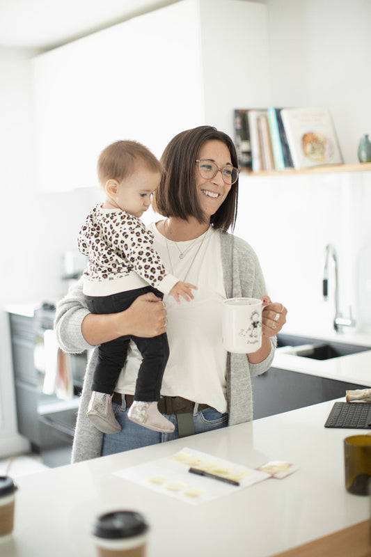 Parent buvant un café en tenant son jeune enfant