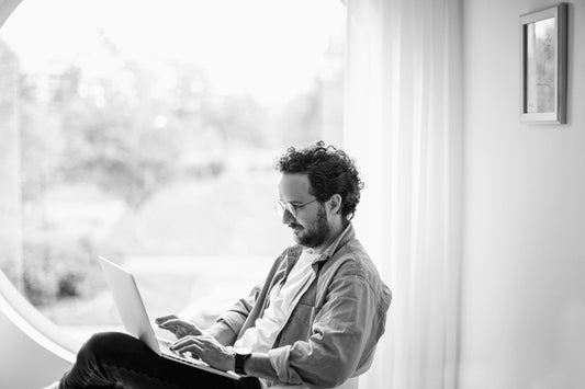 Typing on a laptop by a window