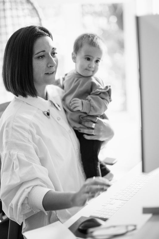 Travailler sur un ordinateur en tenant son enfant