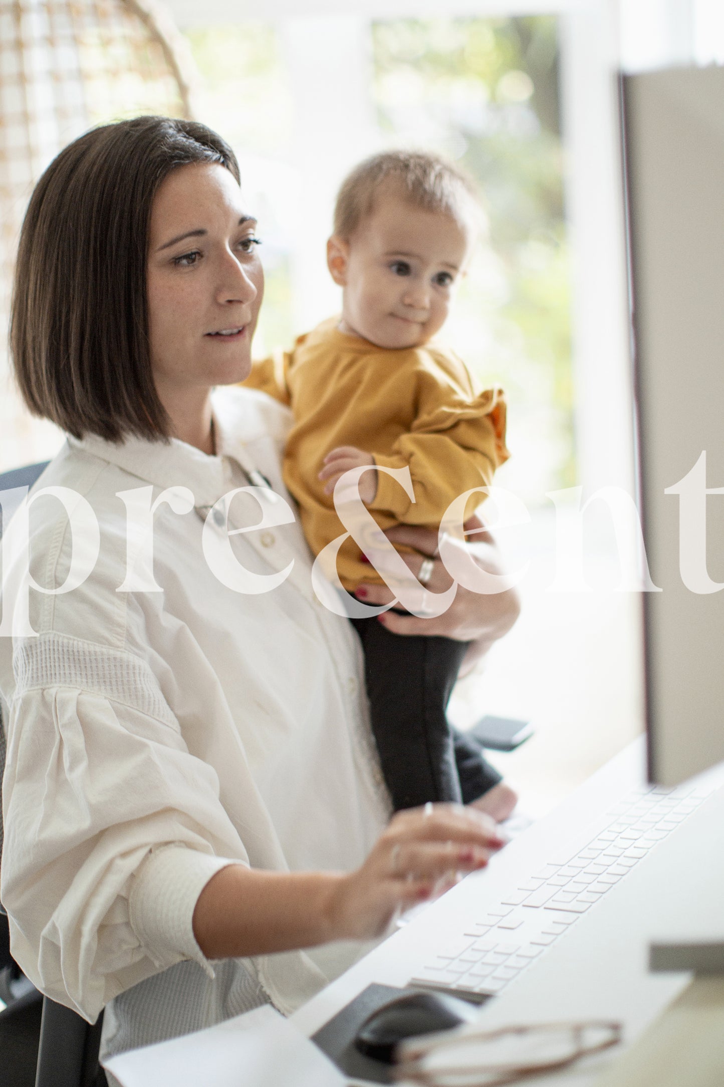 Travailler sur un ordinateur en tenant son enfant