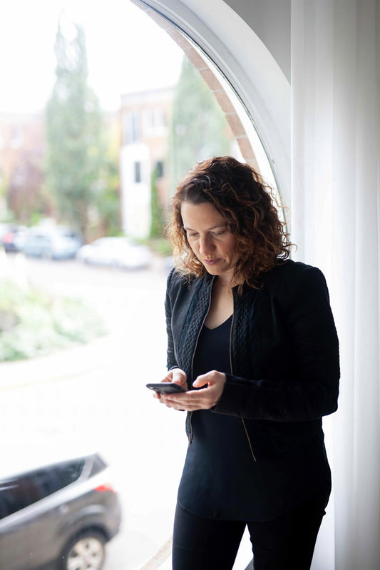 Person typing on their phone near a window